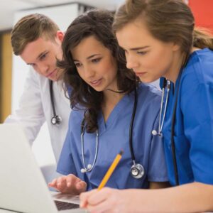 Three Medical Assistants examining a report at a healthcare facility